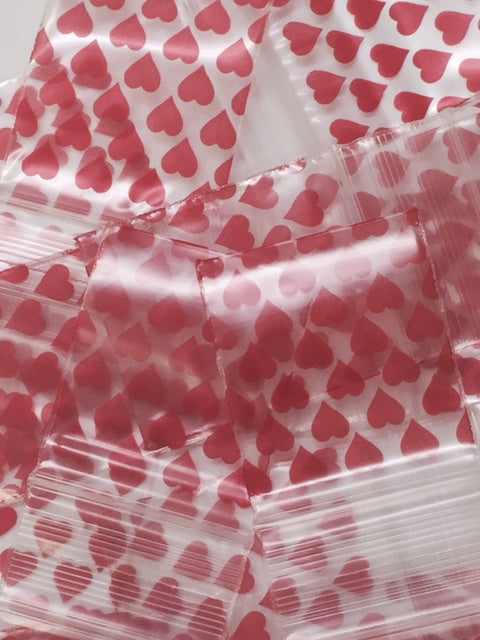 Resealable apple-shaped bags by Original Apple Bags, 1.5 x 1.75 inches with heart designs, ideal for packaging or gift wrapping.